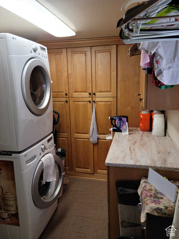Laundry area featuring stacked washer and clothes dryer, cabinet space, and carpet floors