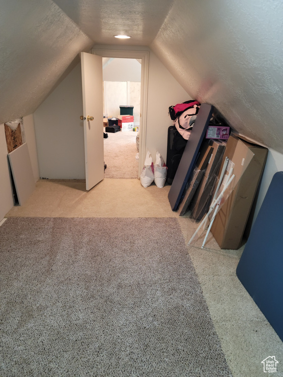Bonus room with a textured ceiling, lofted ceiling, and carpet floors