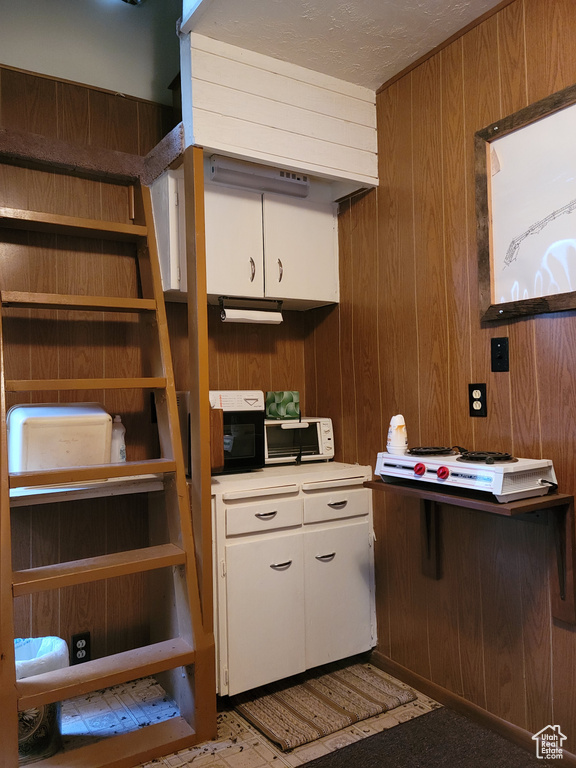 Kitchen featuring wood walls, white cabinetry, and light countertops
