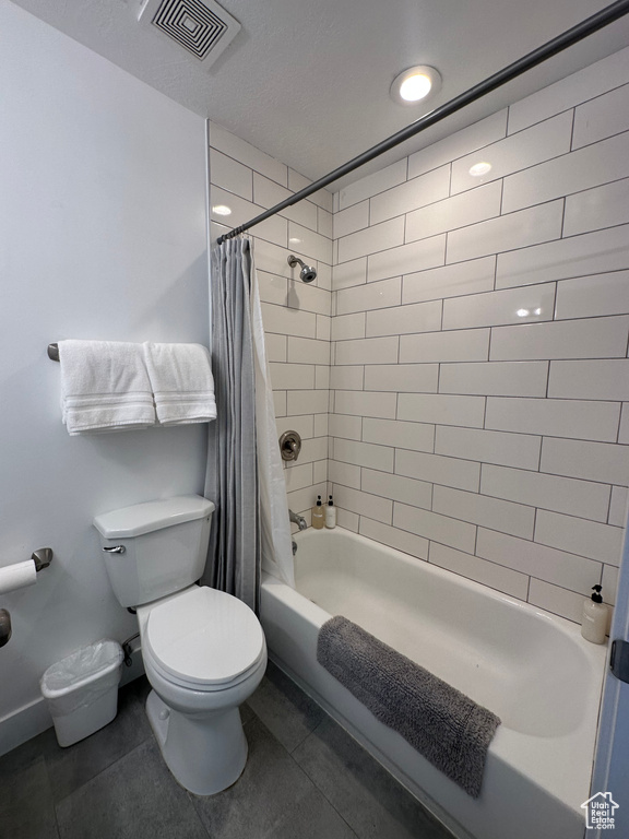 Full bathroom with toilet, shower / bath combination with curtain, and tile patterned flooring