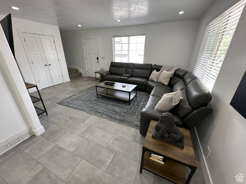 Living room featuring baseboards, recessed lighting, a textured ceiling, and stairway