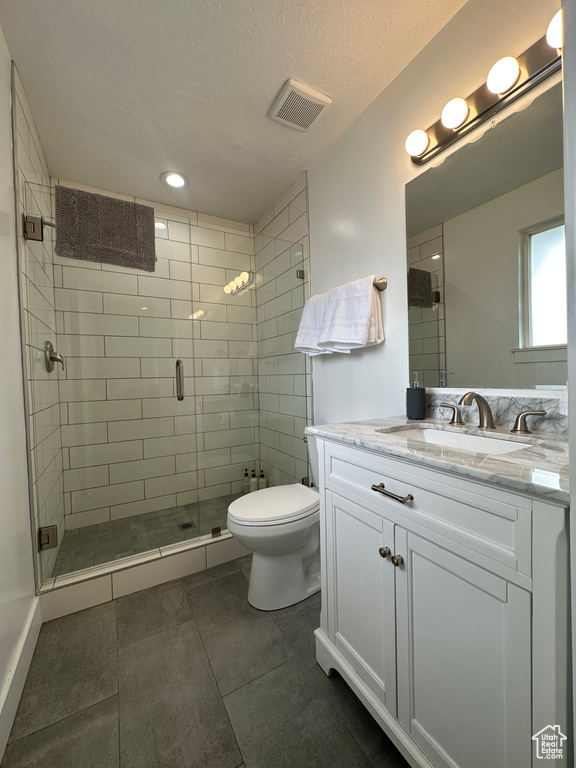Bathroom featuring toilet, a shower stall, vanity, tile patterned flooring, and recessed lighting