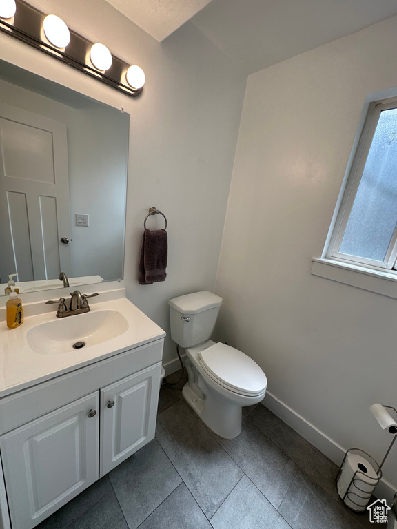 Bathroom with baseboards, toilet, vanity, and tile patterned floors