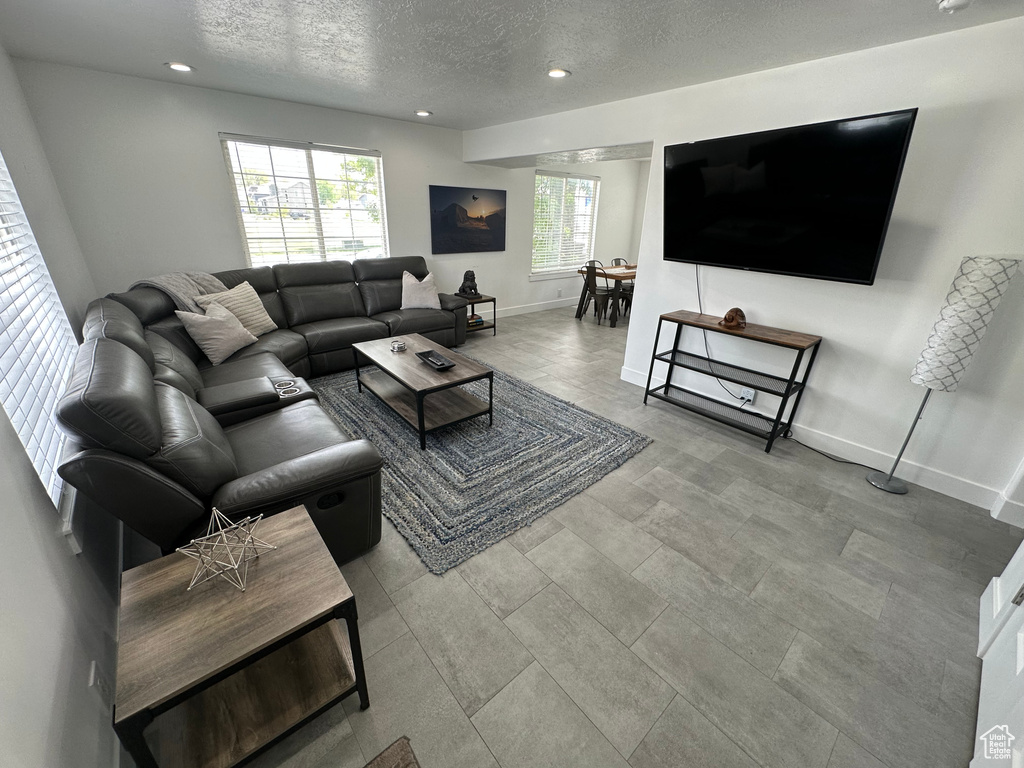 Living room with a textured ceiling, recessed lighting, and baseboards