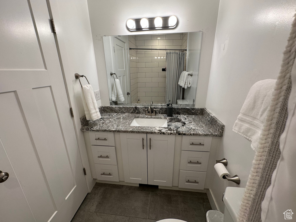 Bathroom with toilet, vanity, tiled shower, and tile patterned floors