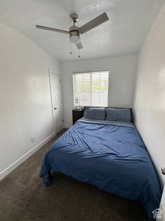 Carpeted bedroom with a textured ceiling, baseboards, and a ceiling fan
