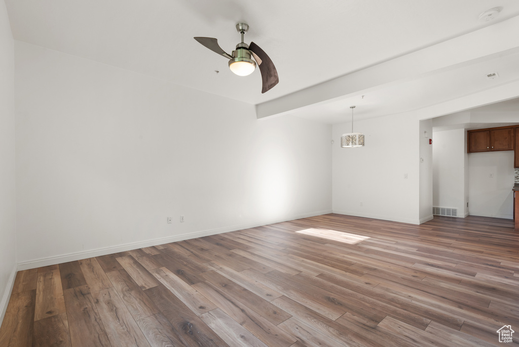 Empty room with wood finished floors, ceiling fan, baseboards, and a smoke detector
