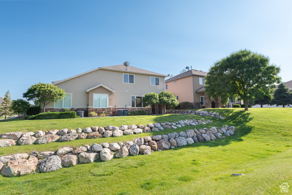 Back of house featuring stucco siding, a yard, and stone siding