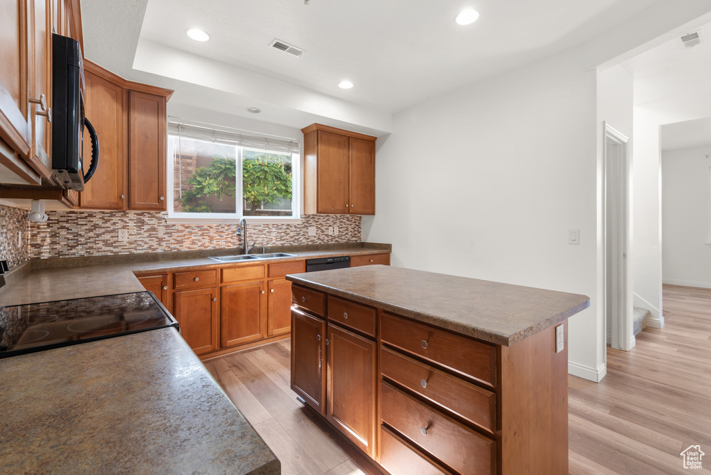 Kitchen with a sink, backsplash, light wood-type flooring, recessed lighting, and a kitchen island