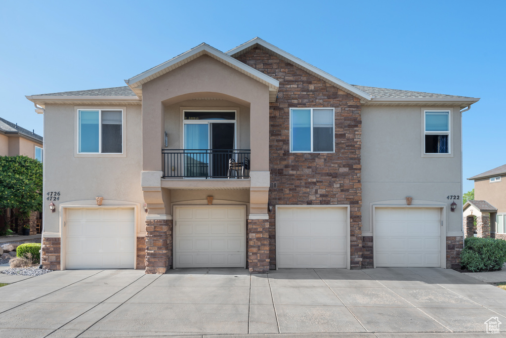 View of front of home with stone siding, stucco siding, a garage, and driveway