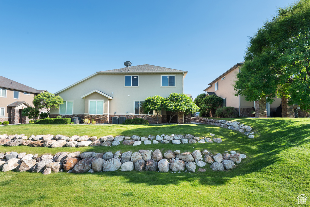Rear view of property with stucco siding, a yard, and central air condition unit
