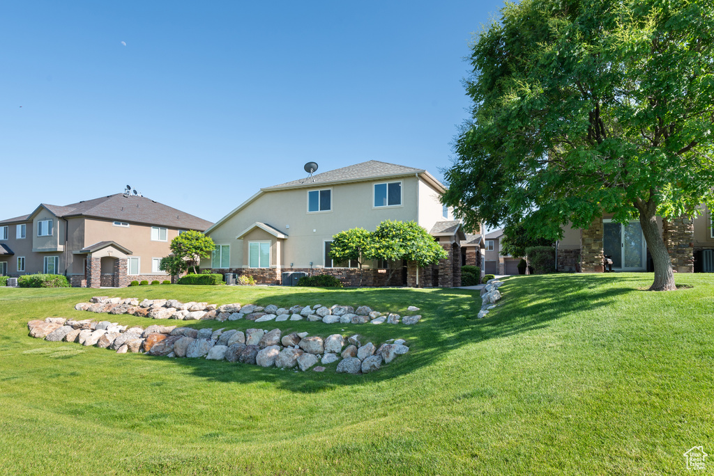 Rear view of property with stucco siding, a lawn, and central AC