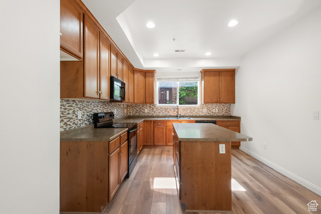 Kitchen with black appliances, a sink, decorative backsplash, a kitchen island, and recessed lighting