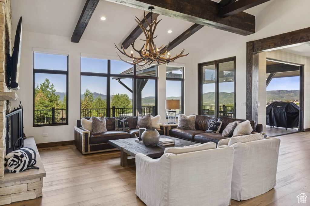 Living room featuring a chandelier, a stone fireplace, healthy amount of natural light, hardwood / wood-style flooring, and recessed lighting