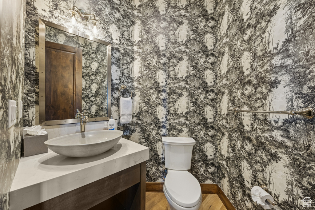 Bathroom featuring wallpapered walls, vanity, and toilet
