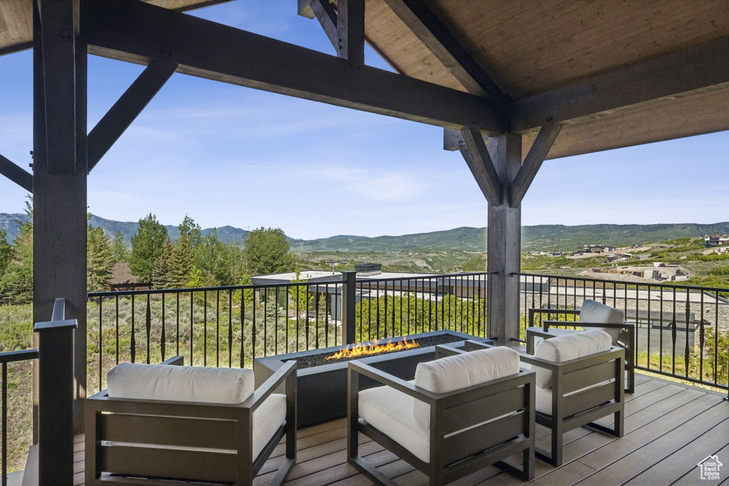 Wooden deck with an outdoor fire pit and a mountain view