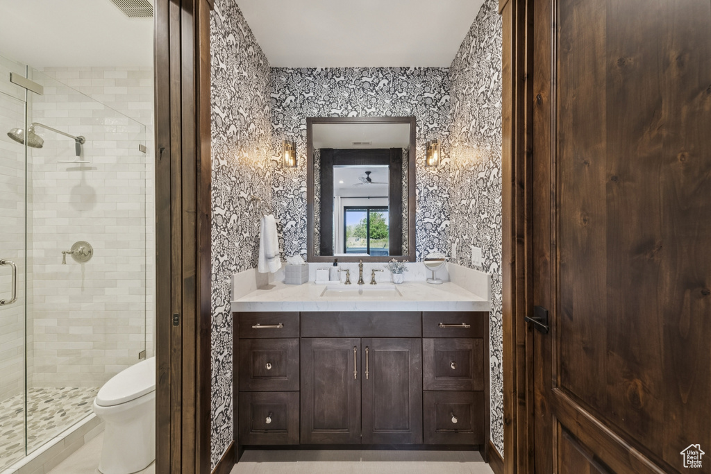Bathroom with a stall shower, vanity, toilet, and wallpapered walls