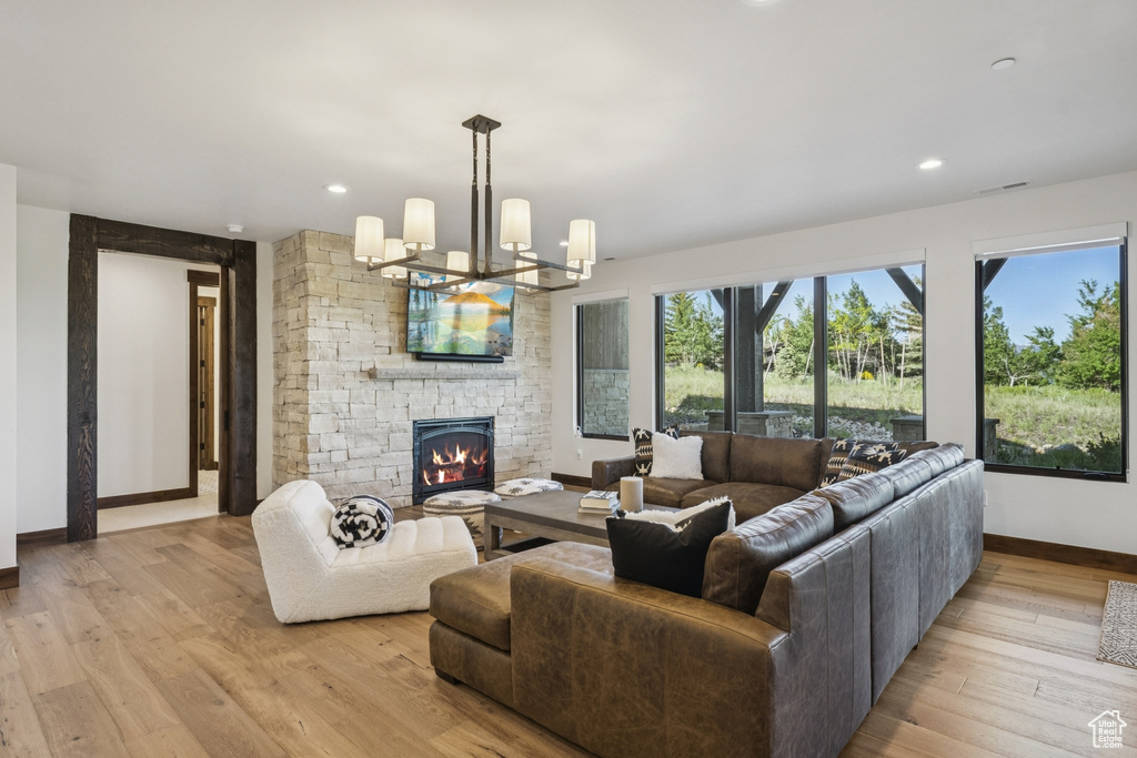 Living room with baseboards, a fireplace, light wood-style flooring, recessed lighting, and a chandelier