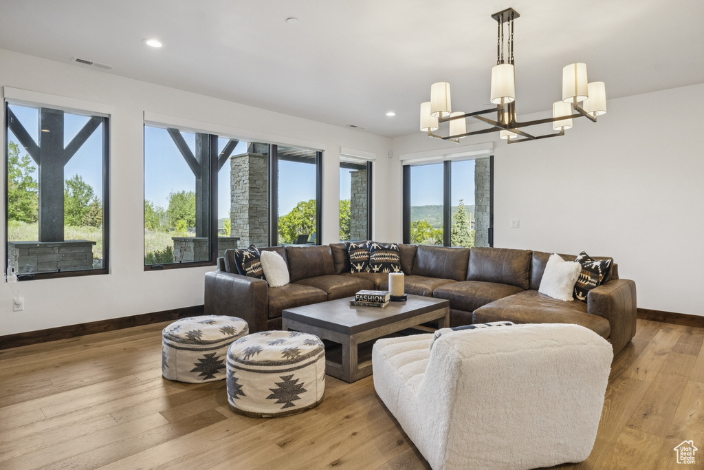 Living area with a chandelier, baseboards, light wood-type flooring, and recessed lighting