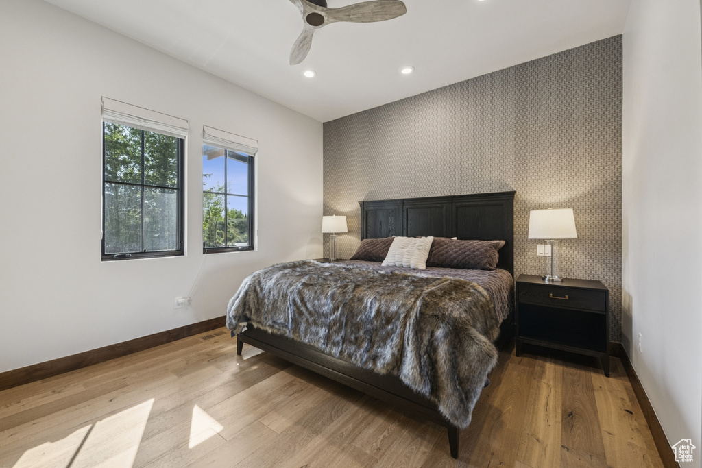 Bedroom featuring an accent wall, baseboards, recessed lighting, wood finished floors, and wallpapered walls