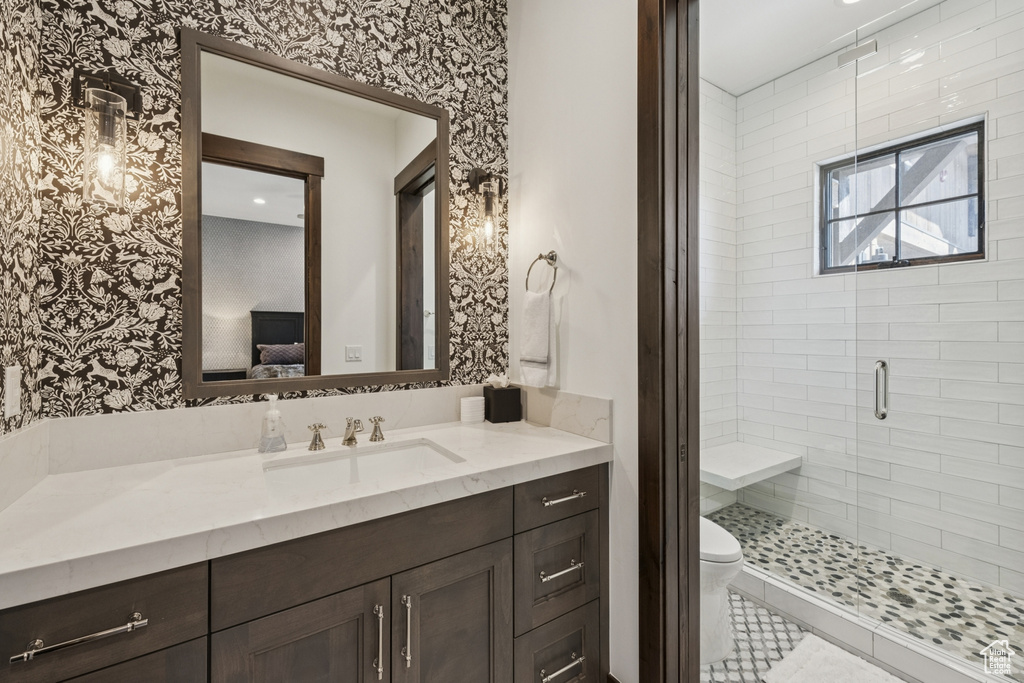 Ensuite bathroom with vanity, wallpapered walls, a stall shower, and toilet