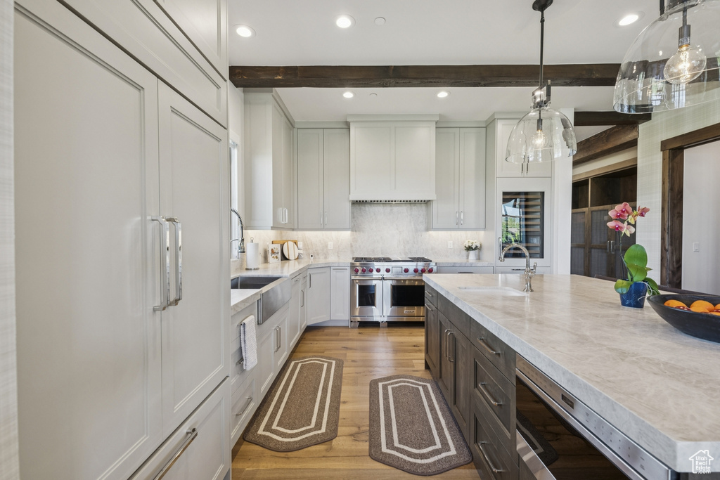 Kitchen with built in appliances, premium range hood, a sink, wood finished floors, and beamed ceiling