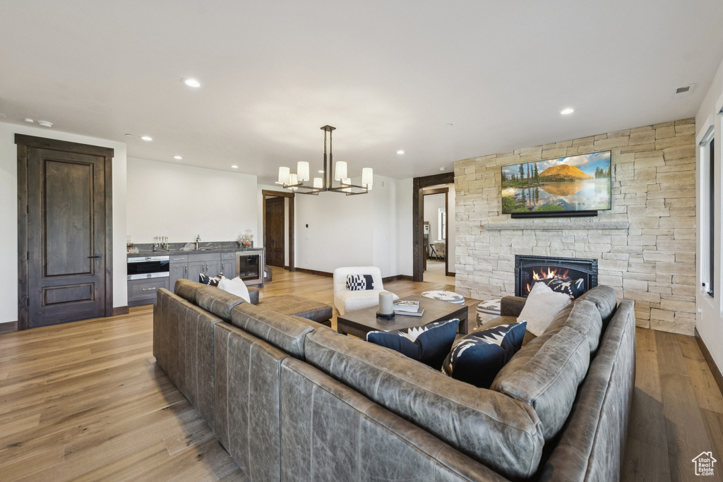 Living area with a fireplace, a chandelier, light wood-style flooring, recessed lighting, and baseboards