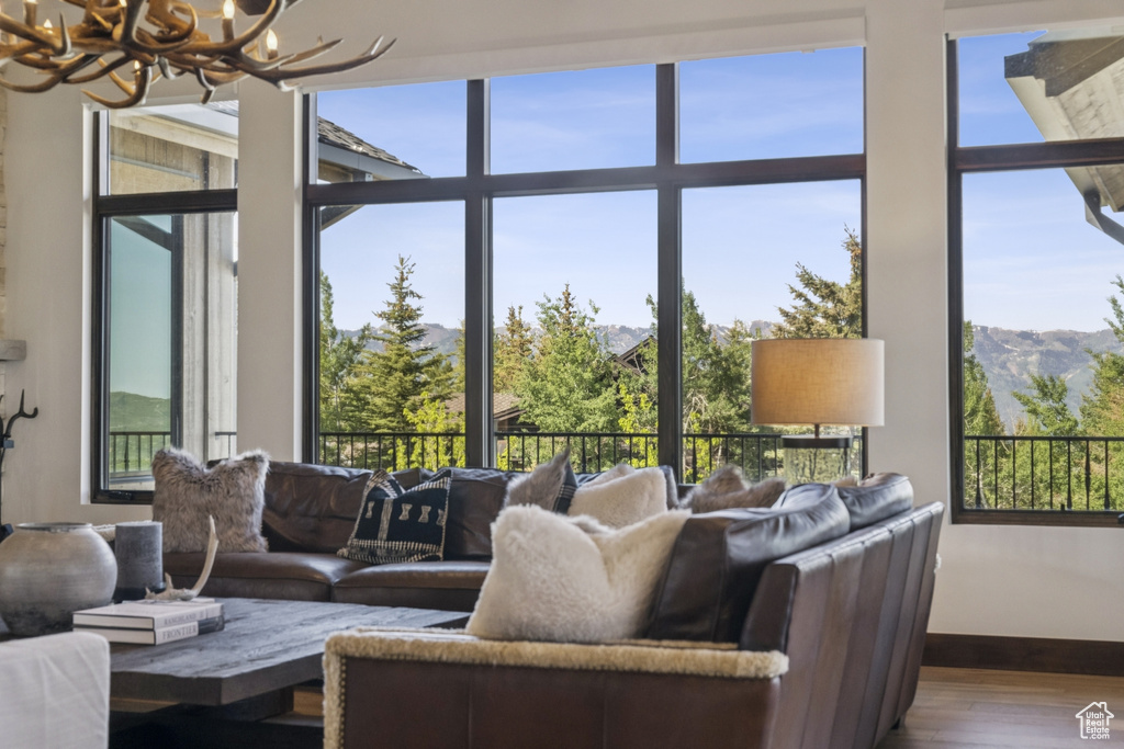 Living area featuring a chandelier, wood finished floors, baseboards, a mountain view, and plenty of natural light
