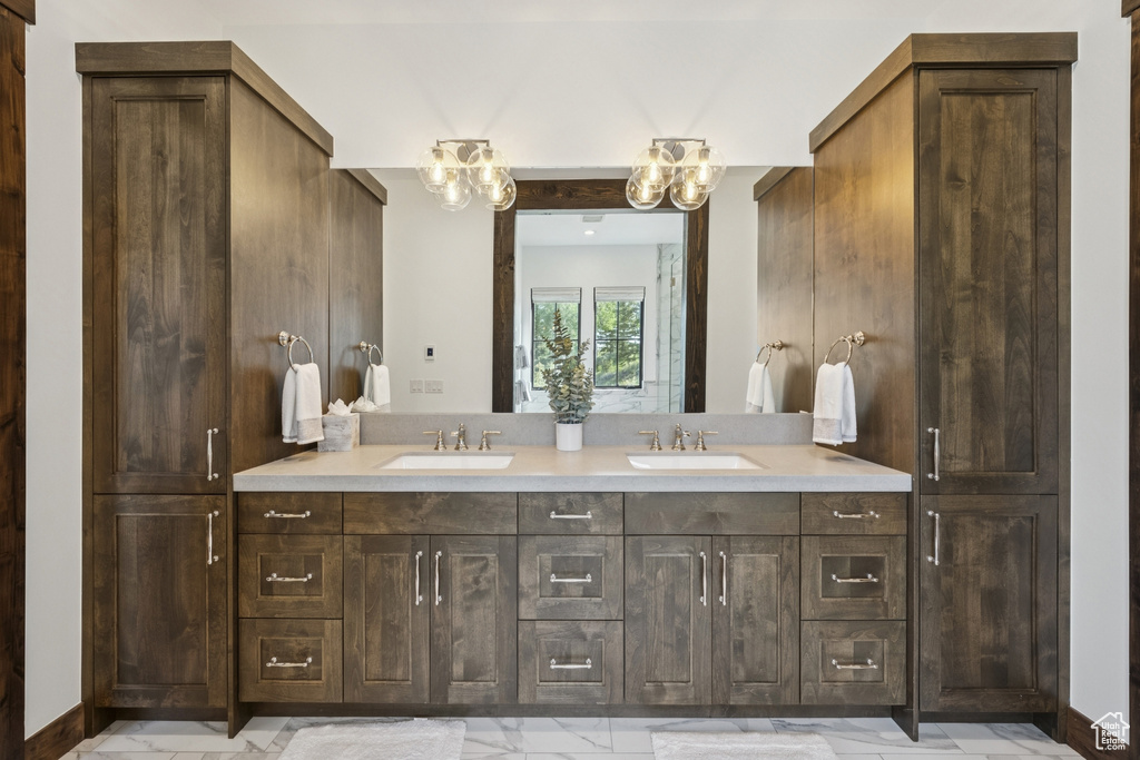 Full bathroom with double vanity, a chandelier, and marble finish floors