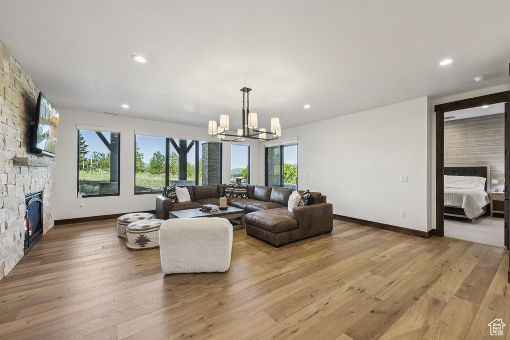 Living room featuring a chandelier, a fireplace, baseboards, light wood finished floors, and recessed lighting