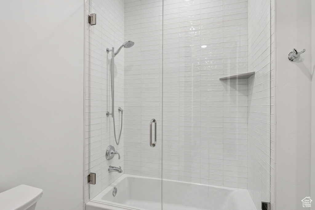 Bathroom with toilet and combined bath / shower with glass door