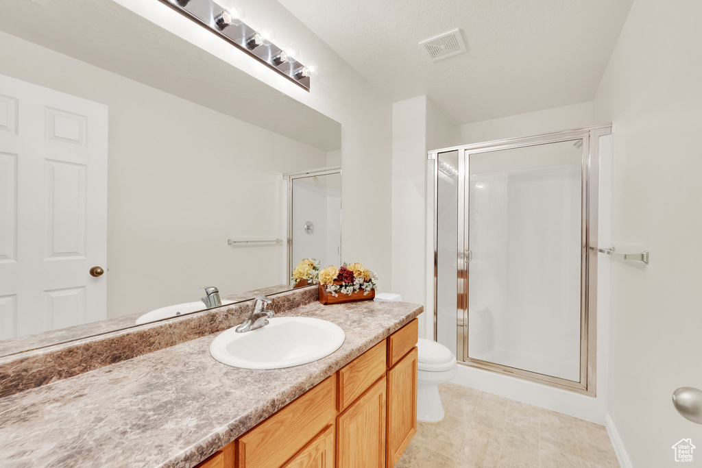 Bathroom featuring toilet, a shower stall, and vanity