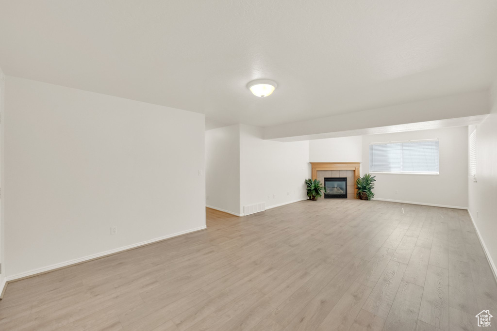 Unfurnished living room featuring light wood-style flooring, baseboards, and a fireplace