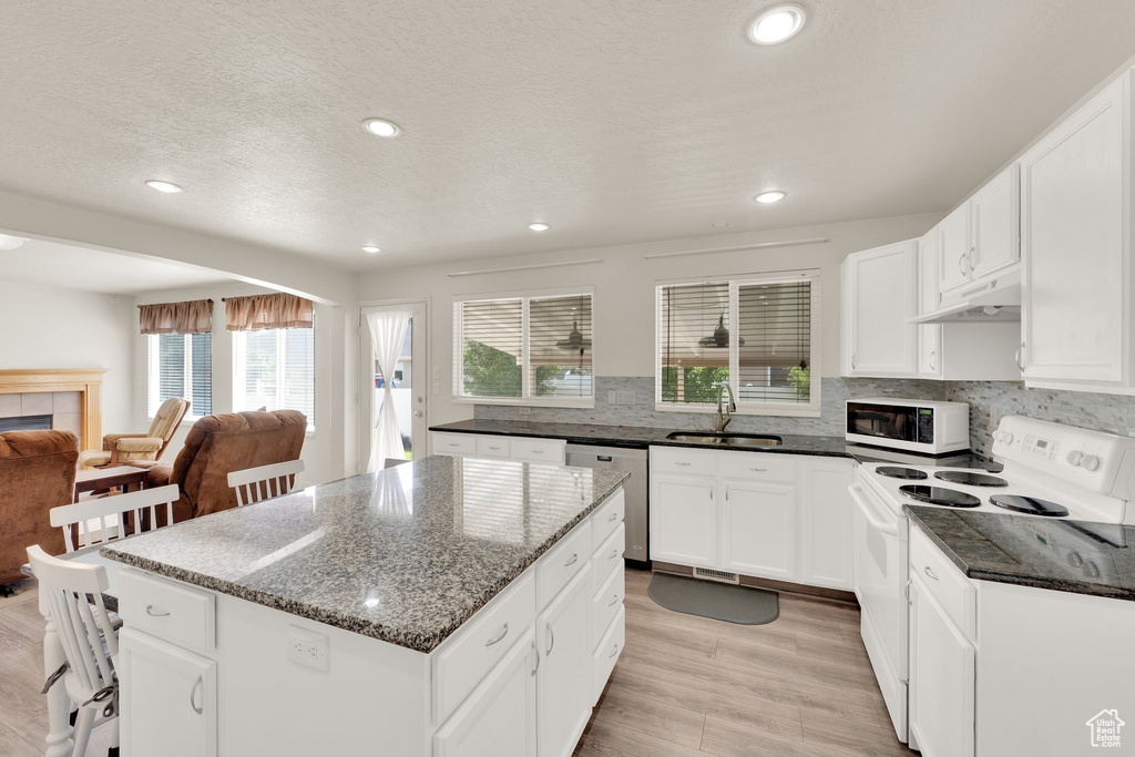 Kitchen featuring white appliances, a sink, under cabinet range hood, healthy amount of natural light, and recessed lighting