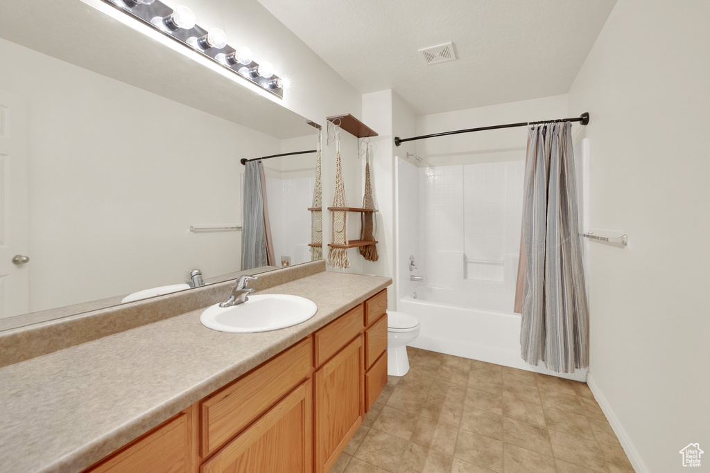 Full bathroom featuring vanity, shower / bathtub combination with curtain, and toilet