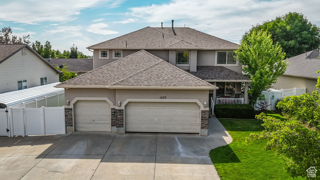 Traditional home with stucco siding, roof with shingles, stone siding, driveway, and a garage