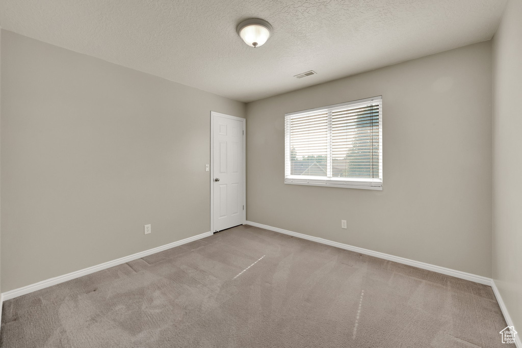 Carpeted empty room featuring baseboards and a textured ceiling