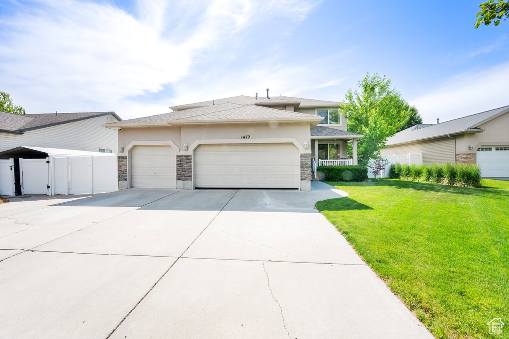 Prairie-style home with stone siding, an attached garage, concrete driveway, stucco siding, and a gate