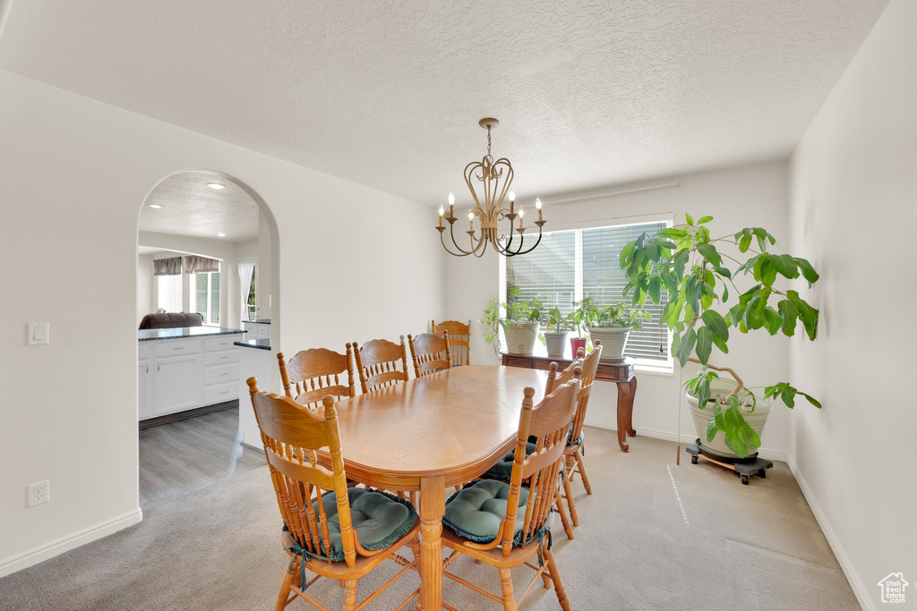 Dining room with arched walkways, a chandelier, light carpet, baseboards, and recessed lighting