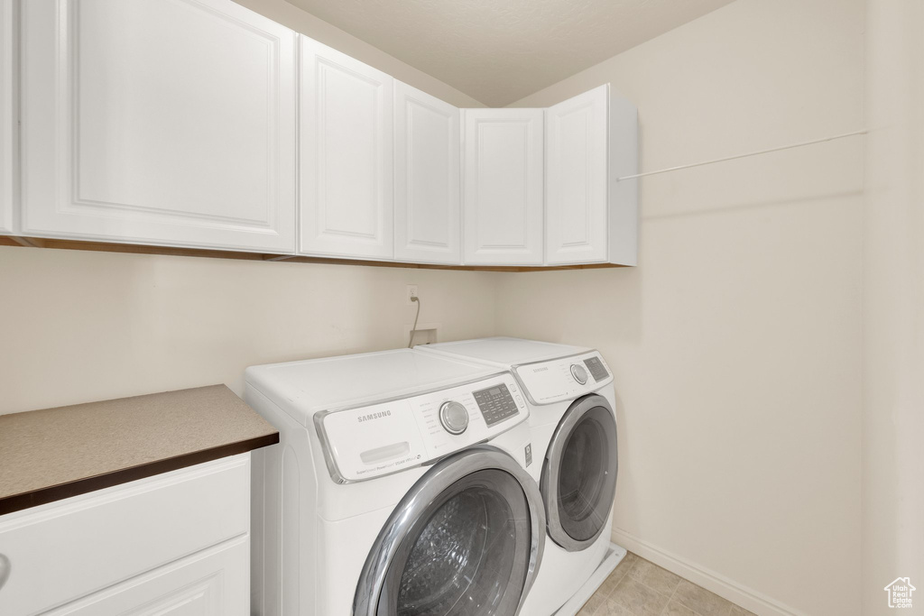 Laundry room with washing machine and clothes dryer, cabinet space, and baseboards
