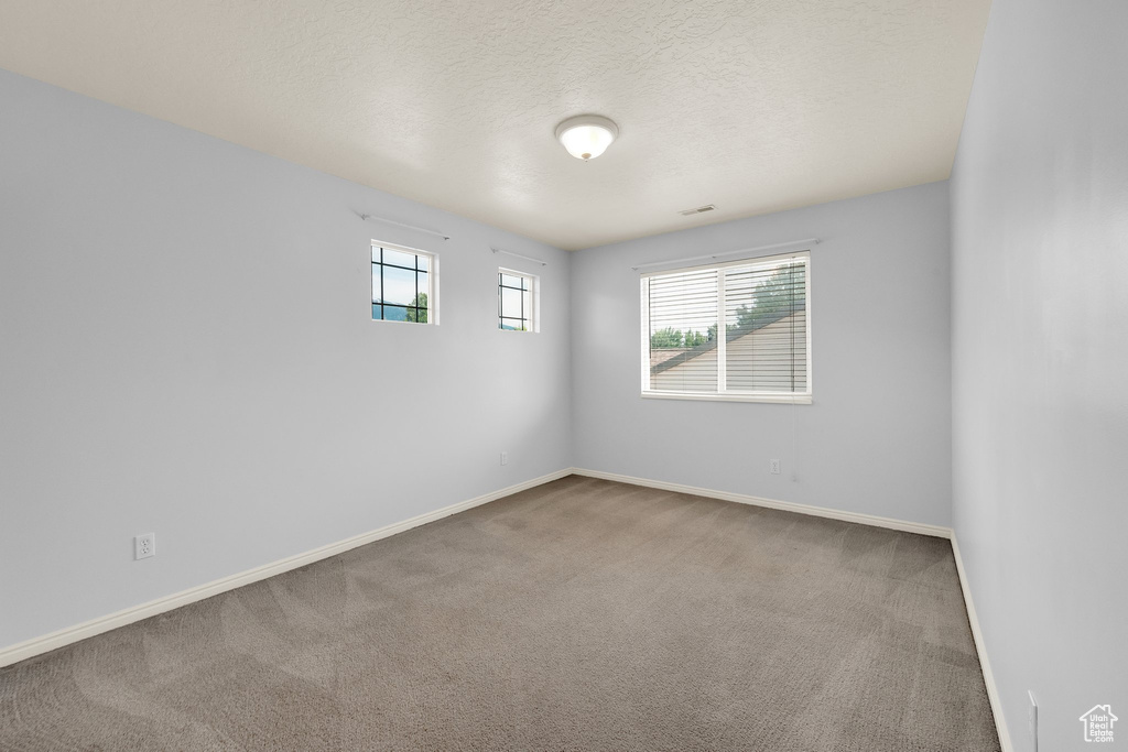 Carpeted empty room featuring baseboards and a textured ceiling