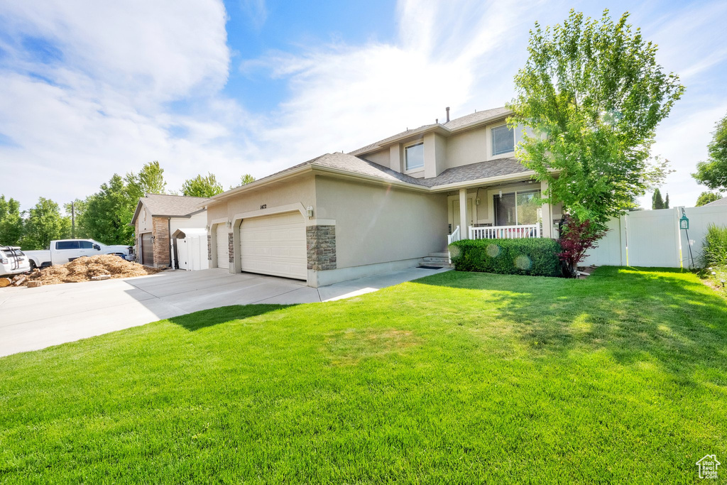 View of front of house featuring stucco siding, an attached garage, driveway, and covered porch