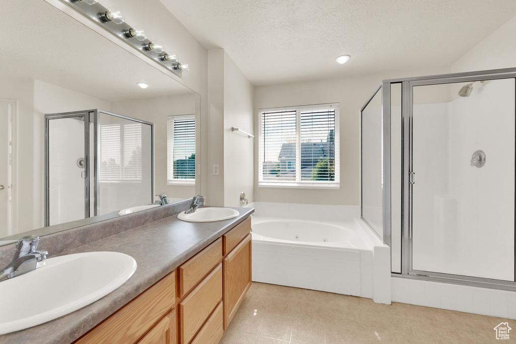 Full bath featuring a shower stall, a tub with jets, double vanity, and tile patterned floors
