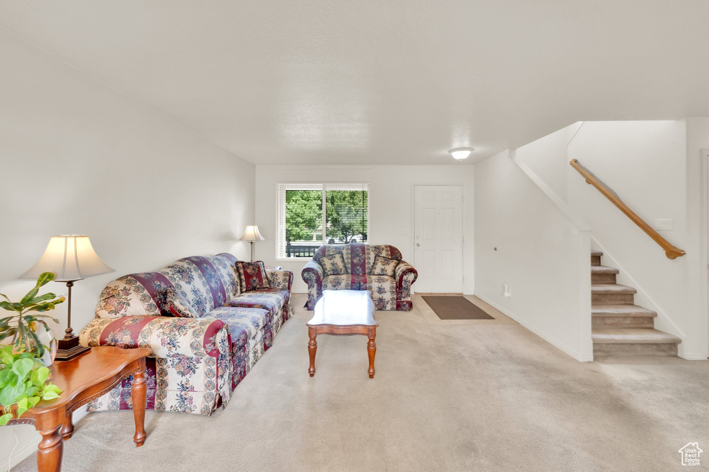 Carpeted living area featuring stairs