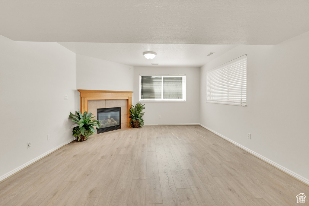 Unfurnished living room with wood finished floors, a fireplace, and baseboards