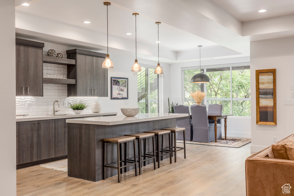 Kitchen with open shelves, modern cabinets, light countertops, a kitchen breakfast bar, and recessed lighting