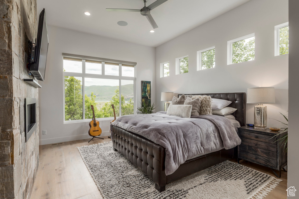 Bedroom featuring light wood-style flooring, baseboards, recessed lighting, a tile fireplace, and a ceiling fan