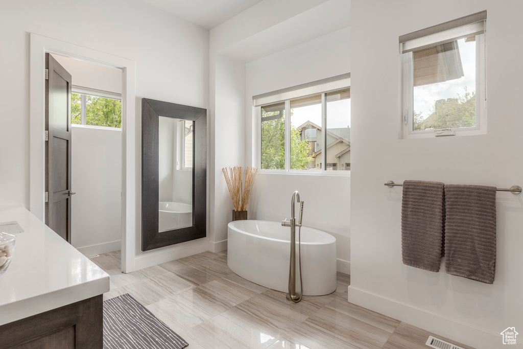 Bathroom featuring a freestanding tub, vanity, and baseboards