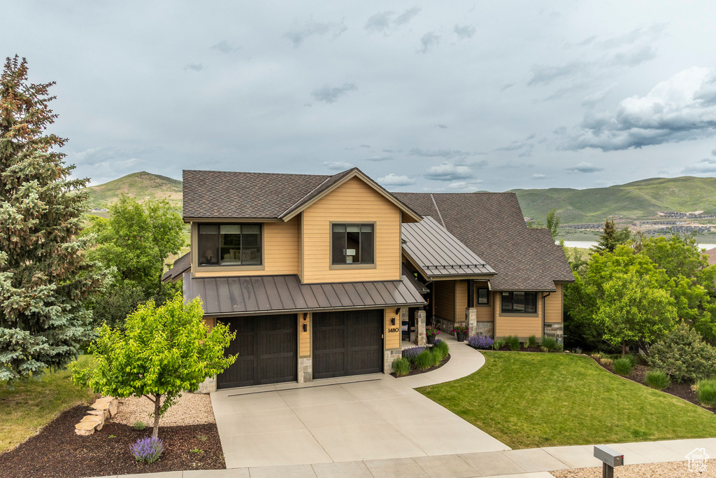 View of front of property with a standing seam roof, metal roof, a garage, a front yard, and a mountain view
