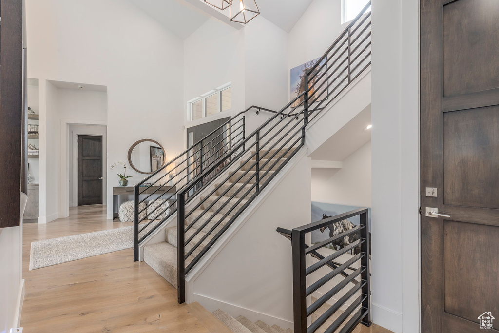 Entrance foyer with a towering ceiling, stairway, light wood-type flooring, and baseboards